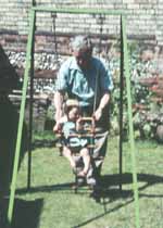 Jacob pushing his daughter on garden swing 